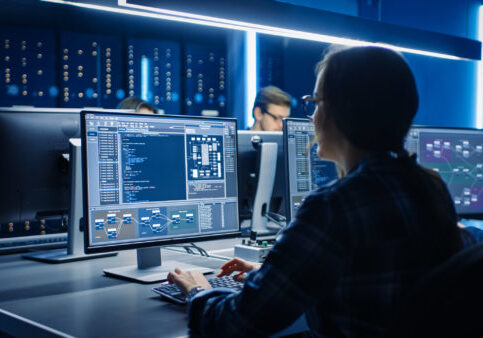 Smart Female IT Programer Working on Desktop Computer in Data Center System Control Room. Team of Young Professionals Doing Code Programming